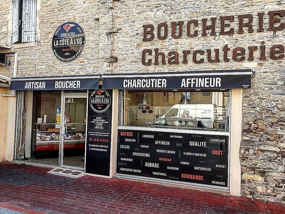 Devanture de la boucherie-charcuterie La Côte À L’os avec mur en pierre