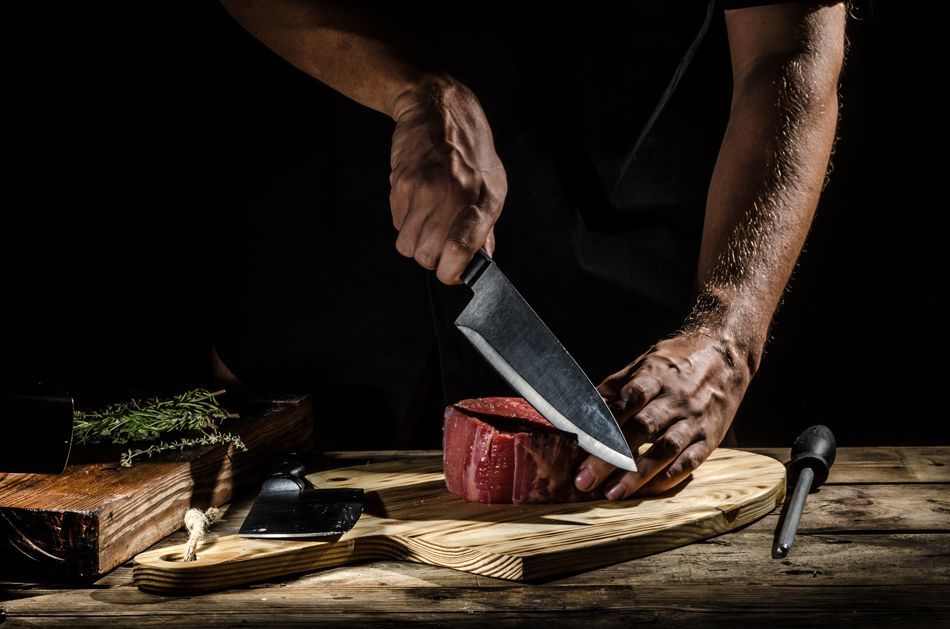 Boucher découpant une pièce de viande avec un couteau de boucher