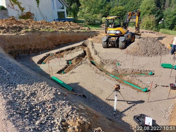 Ein gelber Bagger gräbt ein Loch in die Erde.