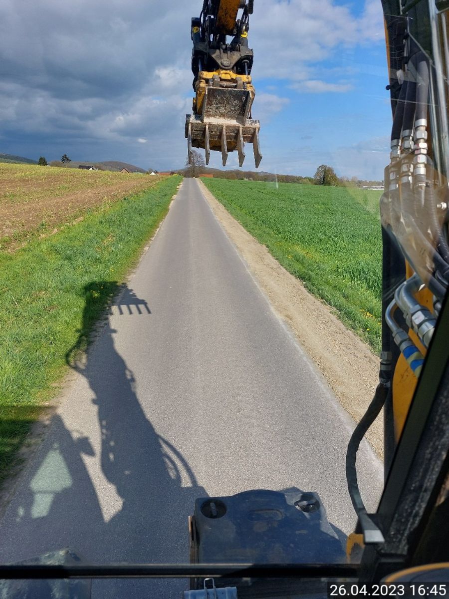 Ein Traktor fährt eine Straße neben einem Feld entlang