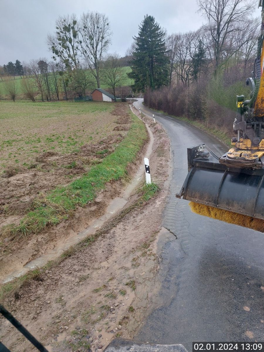 Ein Traktor fährt auf einem Feldweg neben einem Feld entlang.