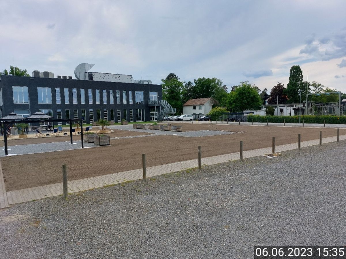 Im Hintergrund ist ein großes Gebäude mit einer Kiesfläche