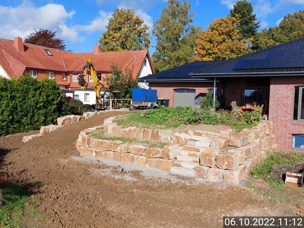 Neben einer Steinmauer wird ein Backsteinhaus gebaut.