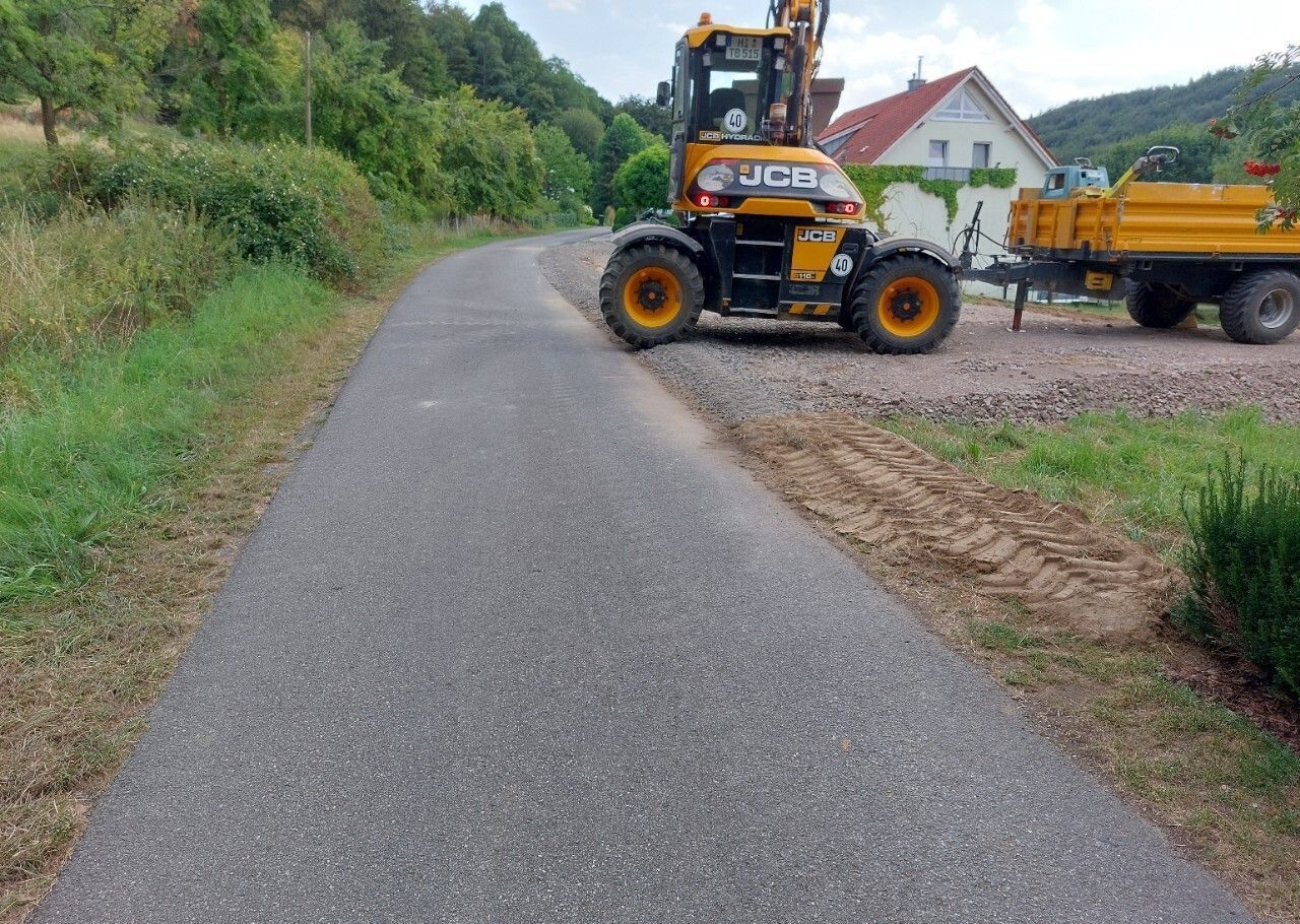 Ein gelber Traktor fährt neben einem gelben Muldenkipper auf einer Straße.