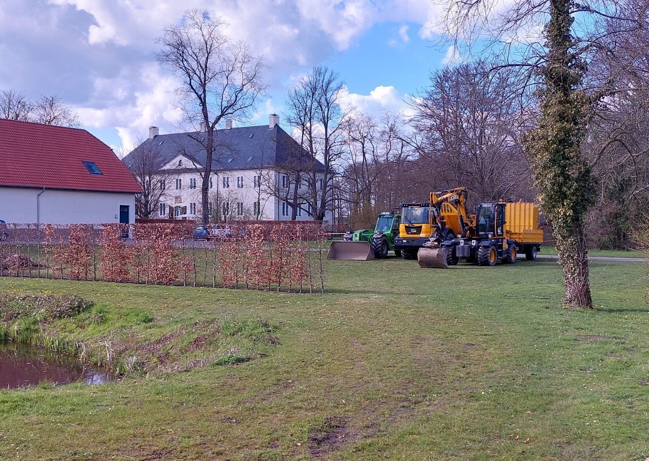 Eine Gruppe von Baufahrzeugen parkt auf einer Wiese vor einem Haus.