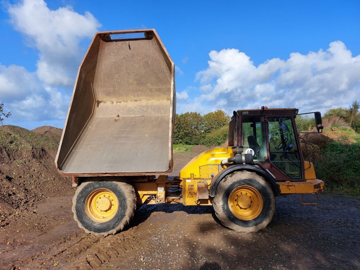 Ein gelber Muldenkipper steht auf einer unbefestigten Straße