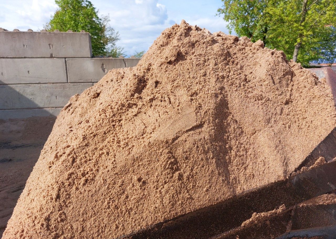 Ein Sandhaufen liegt vor einer Ziegelmauer