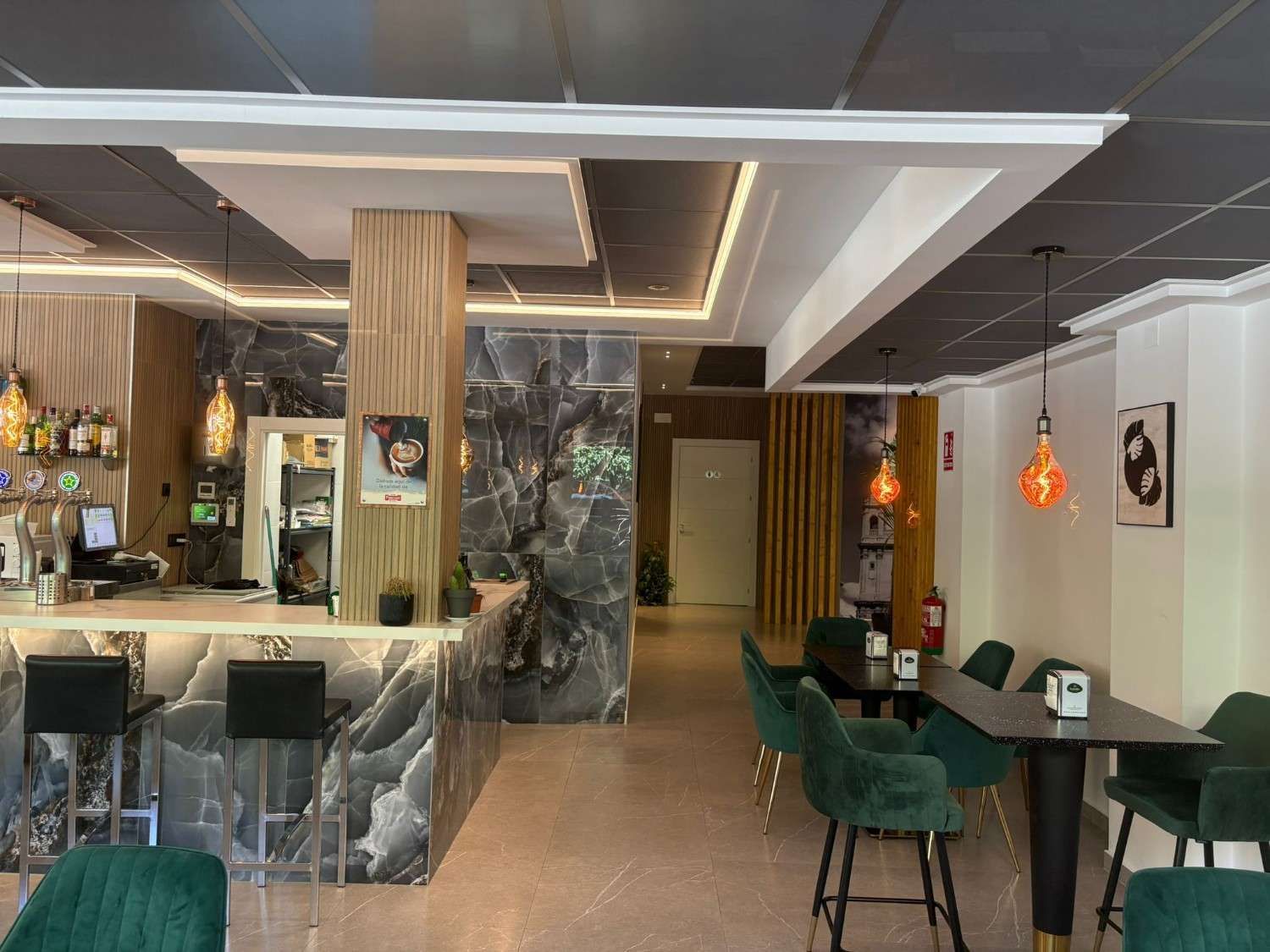 Mesas dispuestas con mantelería blanca, sillas de madera, arte enmarcado en las paredes y un biombo decorativo.