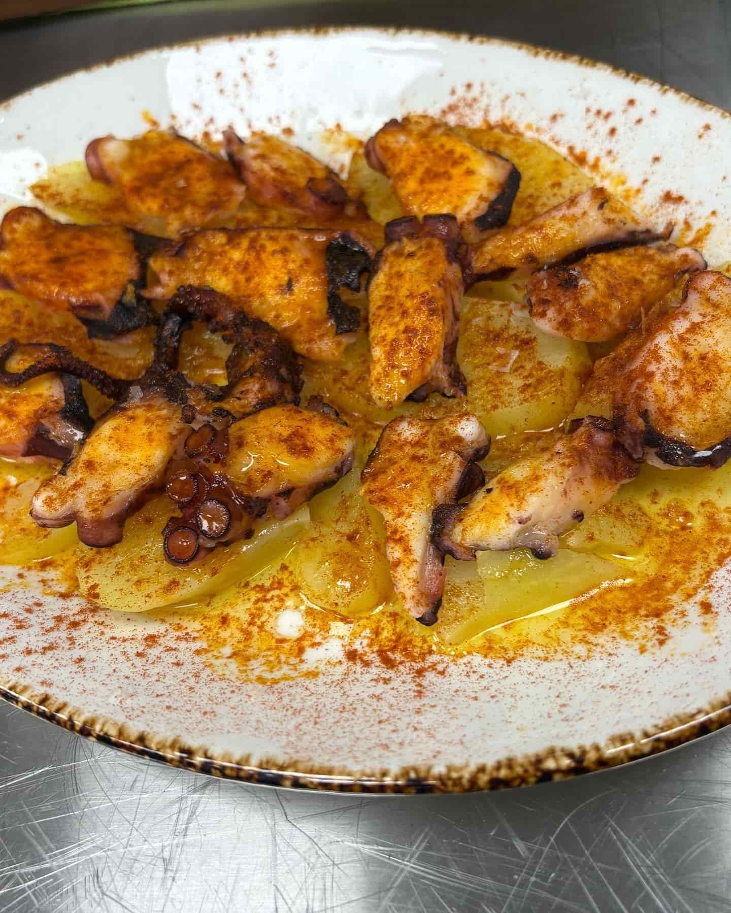 Plato de pulpo: trozos de pulpo a la plancha sobre patatas en rodajas, aderezados con pimentón.