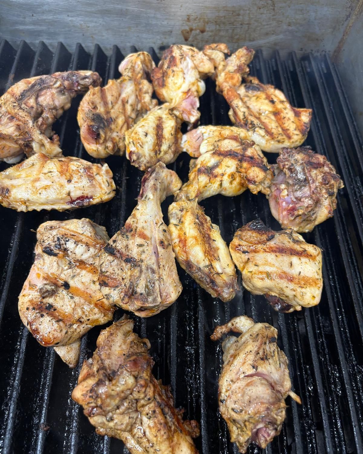 Trozos de pollo asados sobre una parrilla negra, con marcas de parrilla visibles.