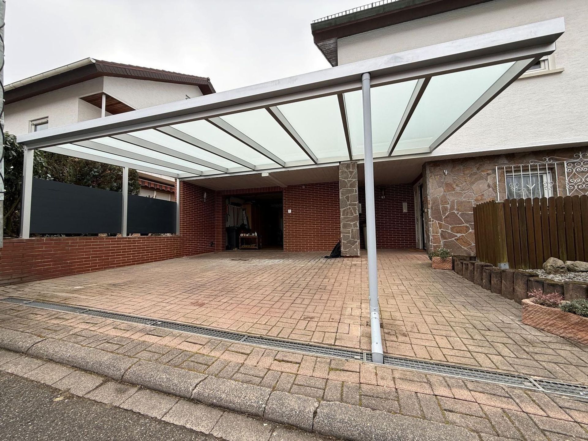 Moderne Hausauffahrt mit Carport, Ziegelpflasterung und schrägem Metallvordach