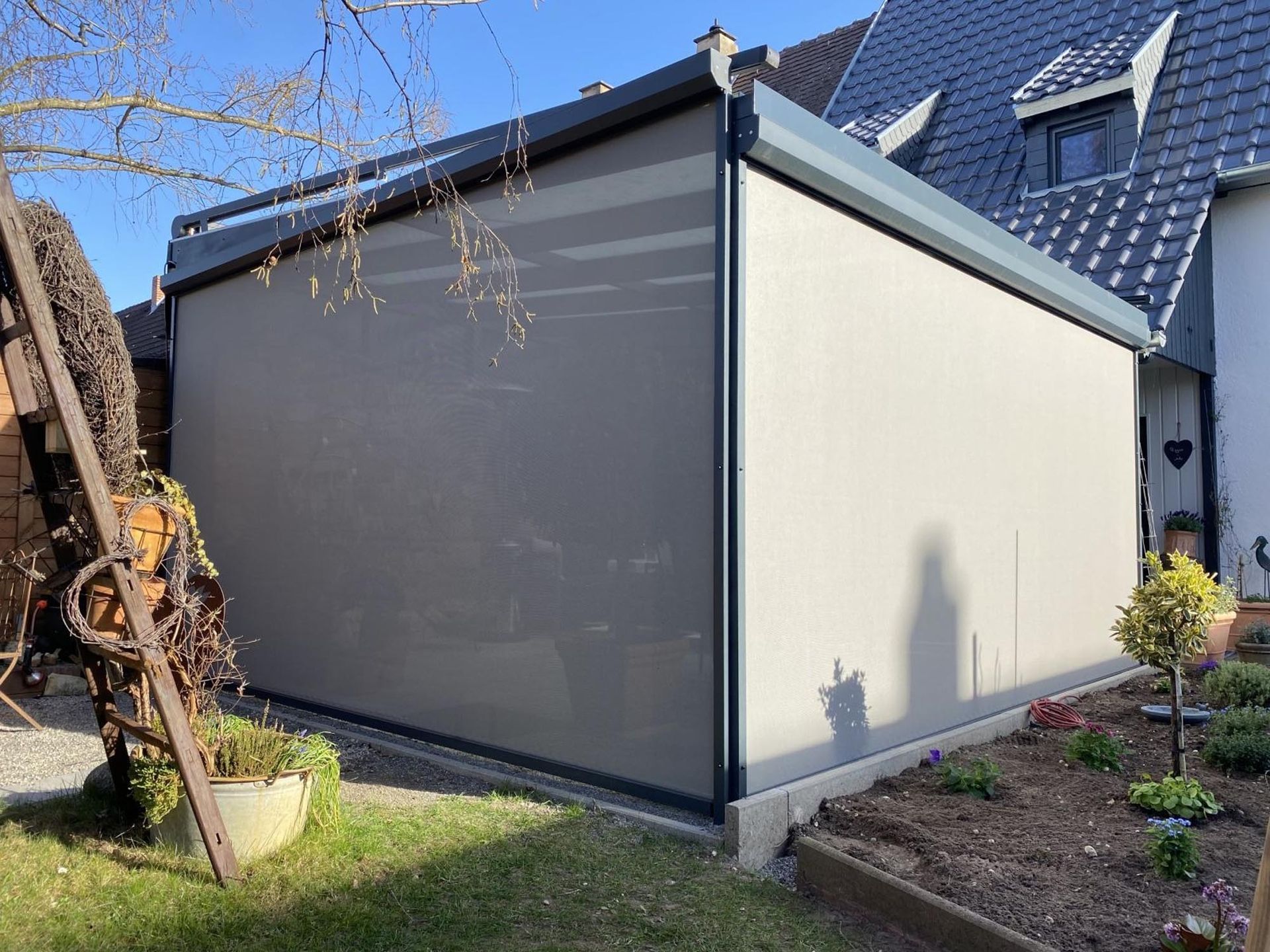 Modernes Hausäußeres mit einer großen, einziehbaren Markise, die eine Terrassenfläche beschattet.