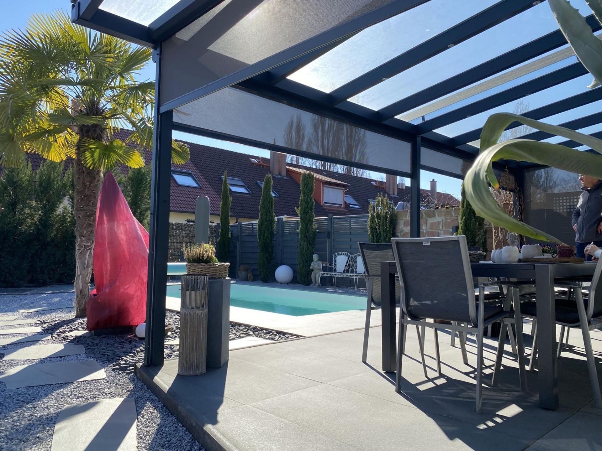 Terrasse mit Pool, Esstisch im Freien und Glaspergola in einem sonnigen Garten