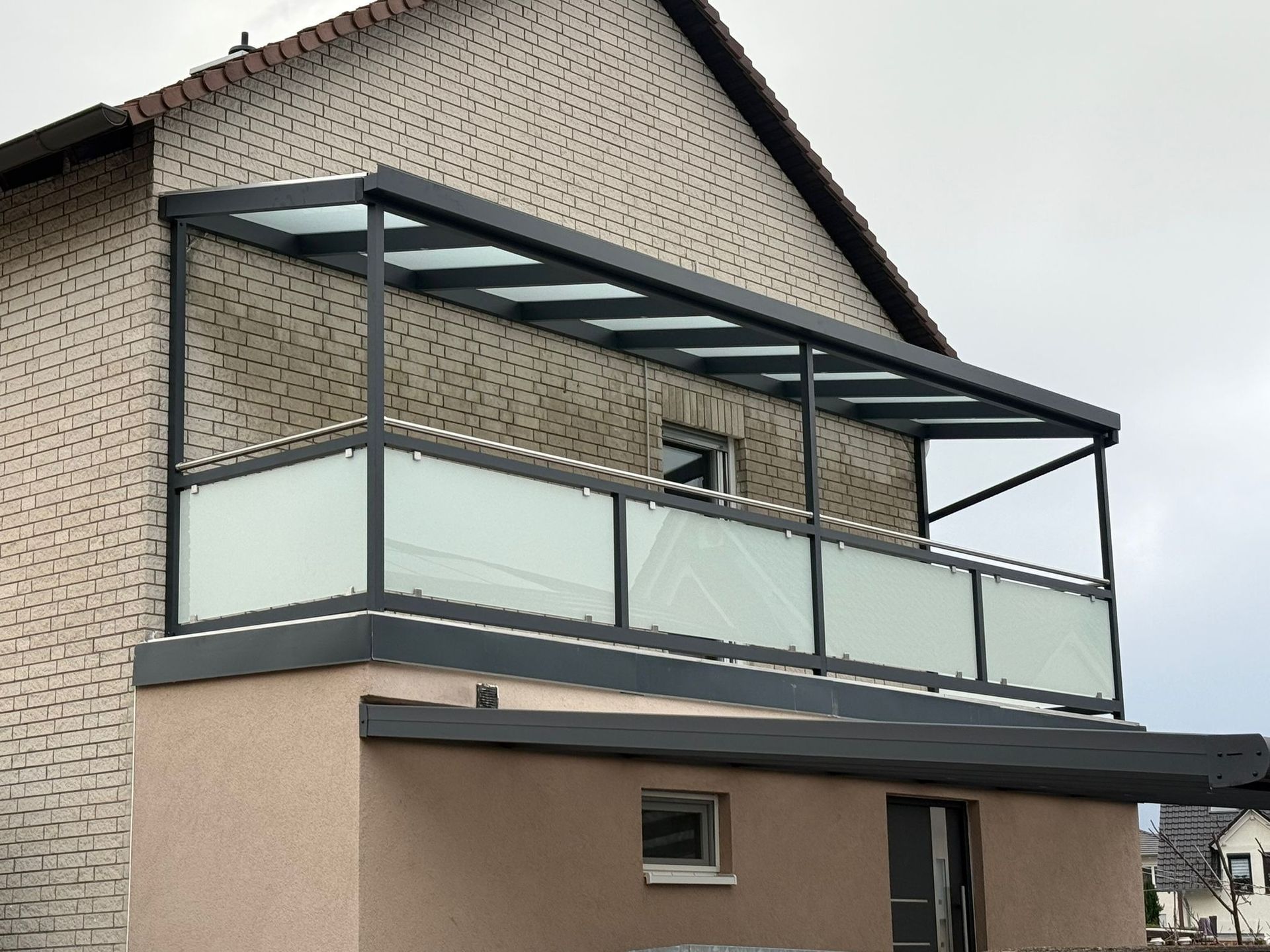 Modernes Haus mit großem überdachten Balkon und Milchglasgeländer im Obergeschoss