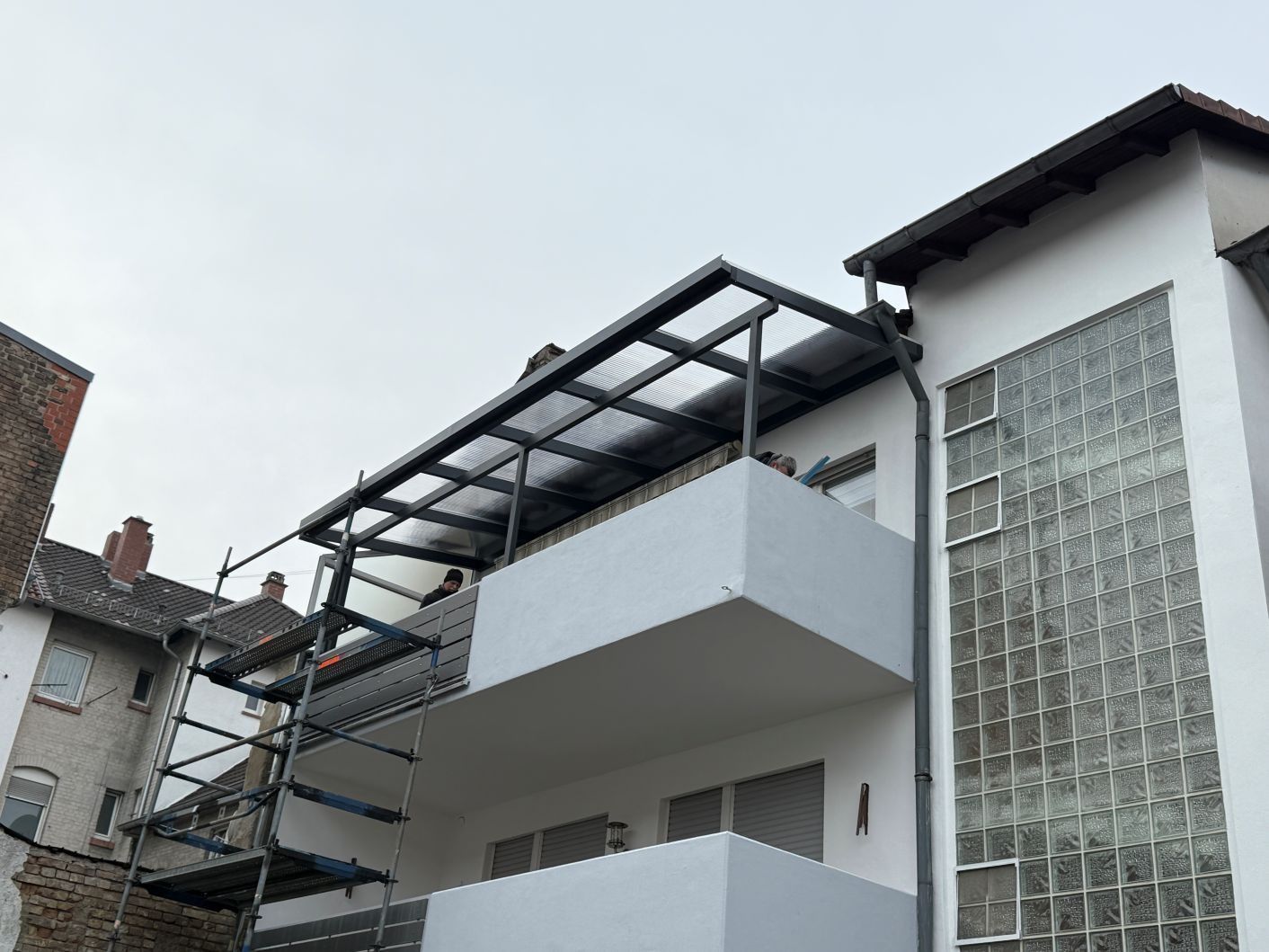 Modernes weißes Mehrfamilienhaus mit Dachterrasse und Glasbausteinfassade