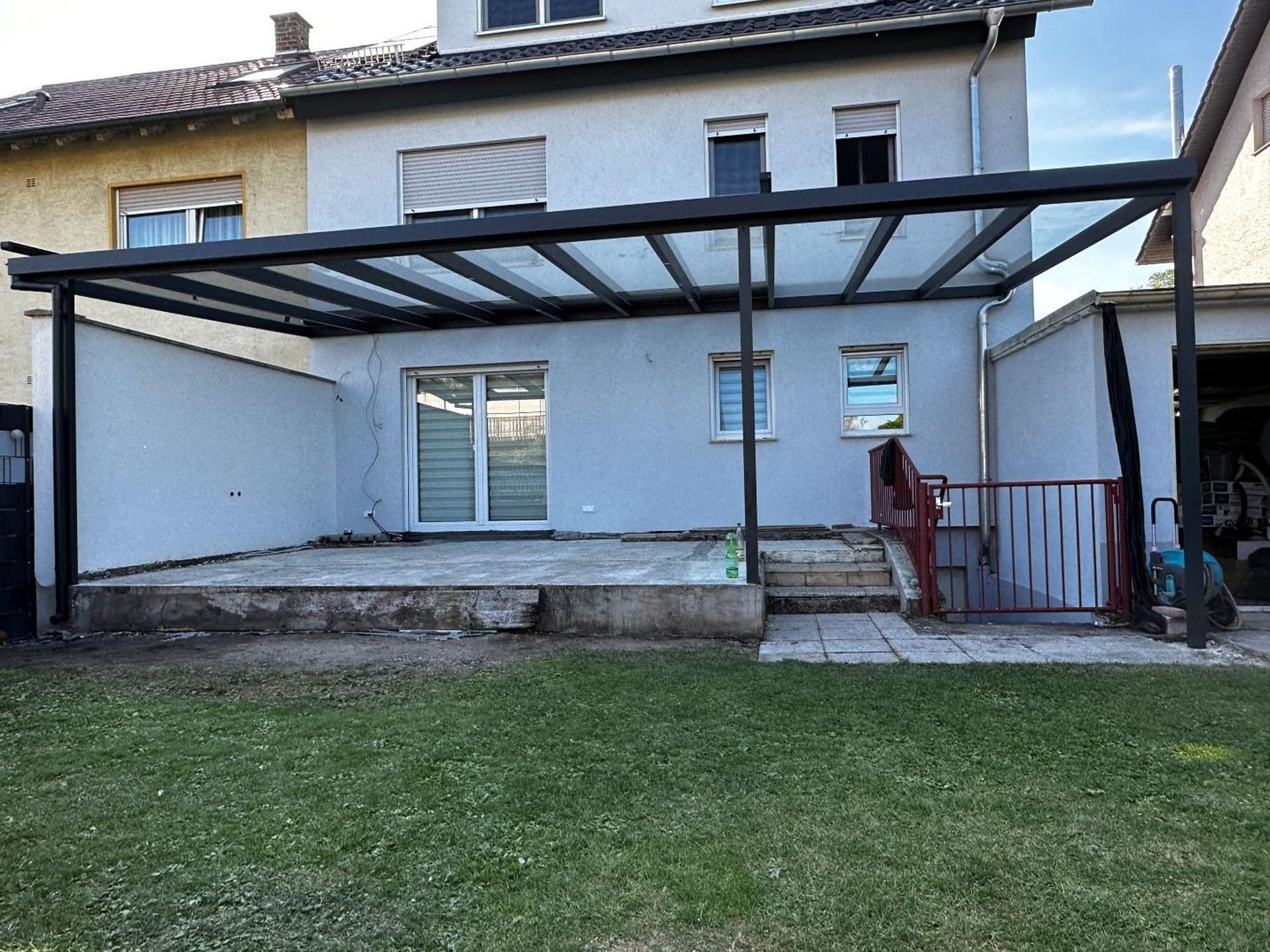 Hinterhofterrasse mit einer großen, an das Haus angebauten Metallpergola