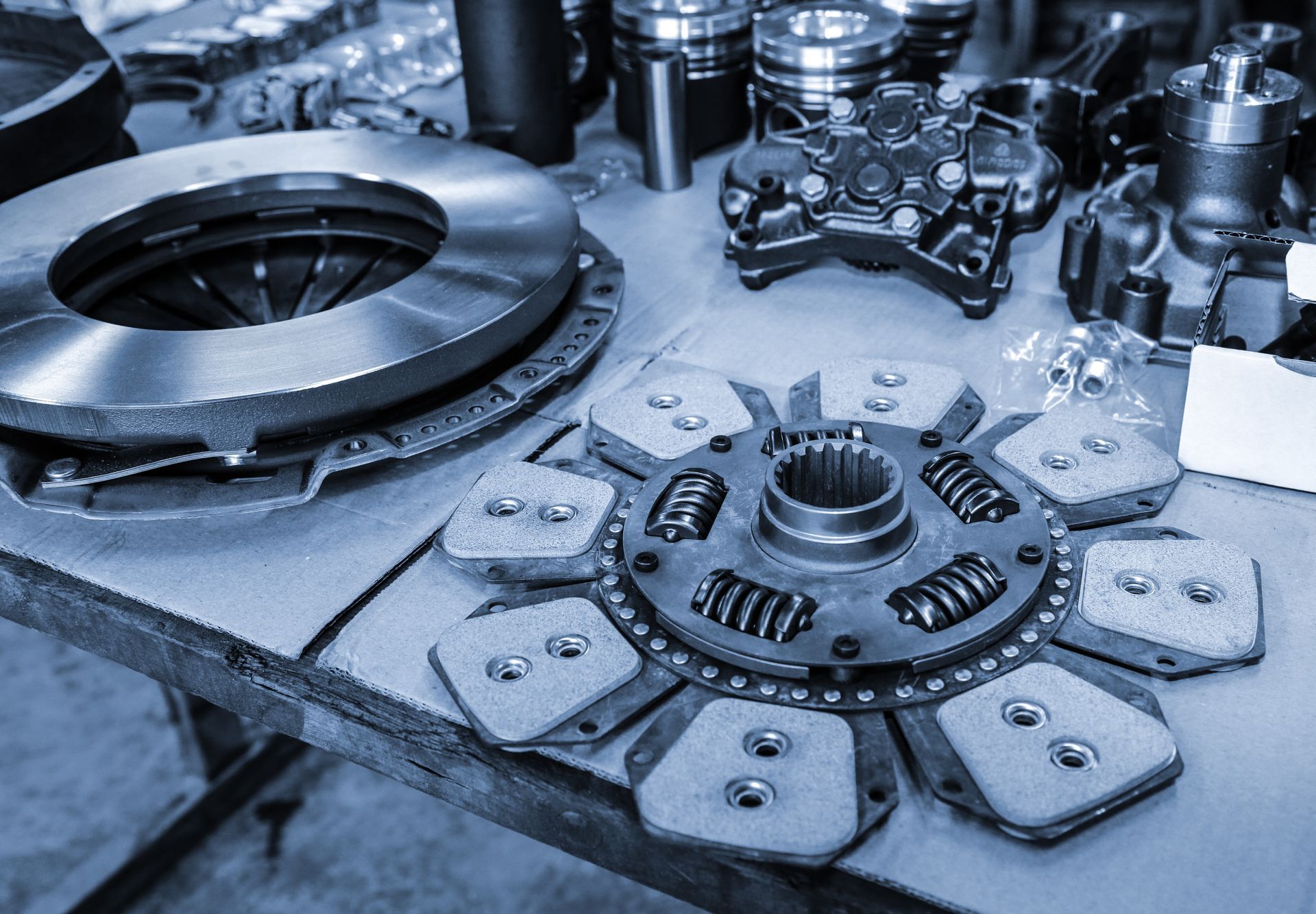 Ensemble d'embrayage et autres pièces automobiles sur une table de travail.