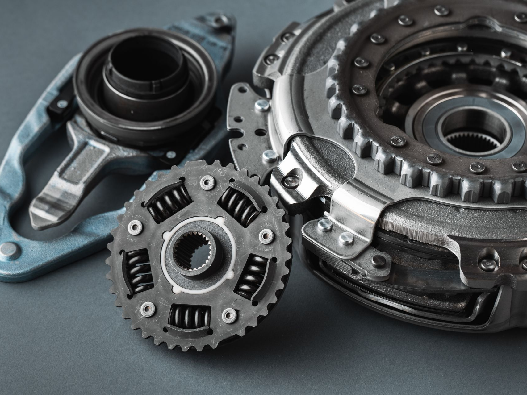 Composants d'embrayage de voiture disposés sur une surface grise.