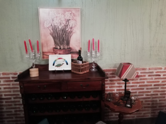 Rincón decorativo en la sala de estar con aparador de madera oscura, velas rojas, cuadros enmarcados