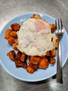 Arroz frito con un huevo frito encima, servido en un plato azul con un tenedor al lado.