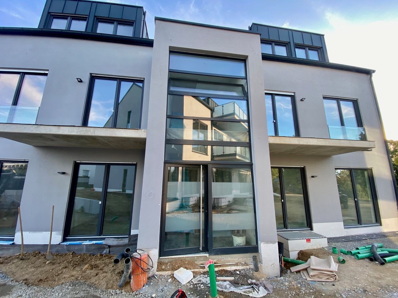 Graues, modernes Gebäude mit großen Fenstern und Balkonen, das sich im Bau befindet.