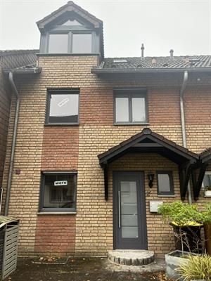 Reihenhaus aus Backstein mit dunkelgrauen Zierleisten, Türen und Fenstern; kleine Eingangsveranda.