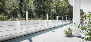 Ein moderner Balkon mit einem Geländer aus Glas und Metall bietet Aussicht auf eine üppig grüne Baumreihe.