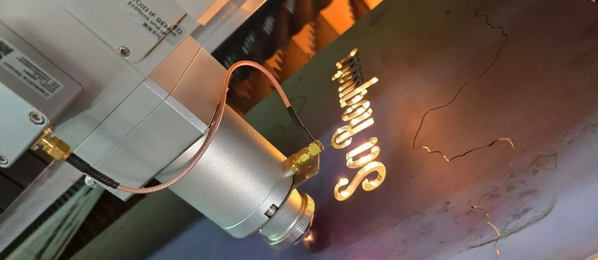 Máquina de grabado láser que graba las palabras "Sa Sergey DS" sobre una superficie oscura.