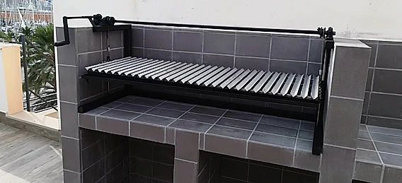 Barbacoa exterior empotrable con rejilla metálica, colocada en estructura de baldosa.