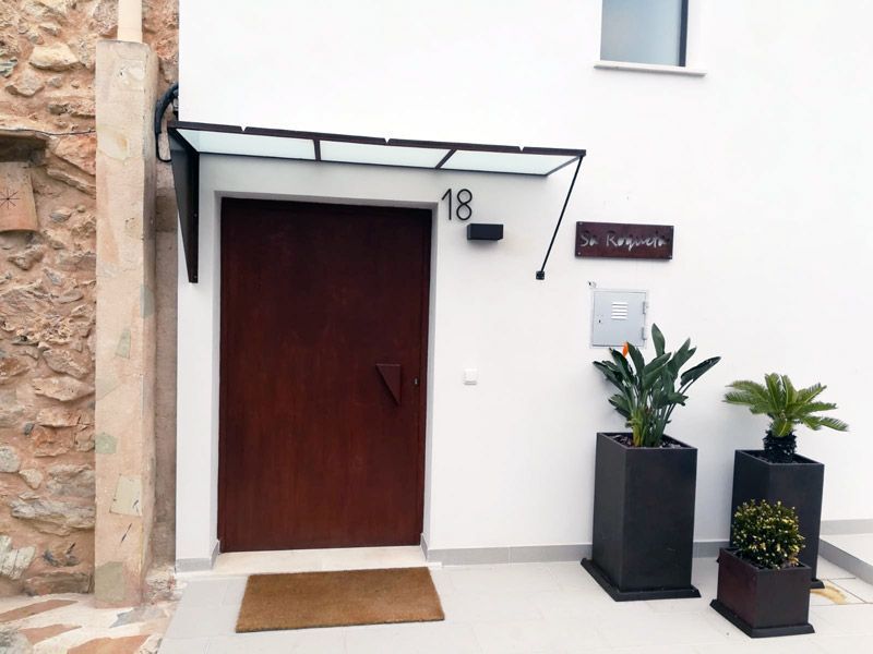 Puerta marrón con toldo, dirección 