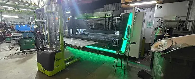 Carretilla elevadora en almacén con maquinaria e iluminación de neón.