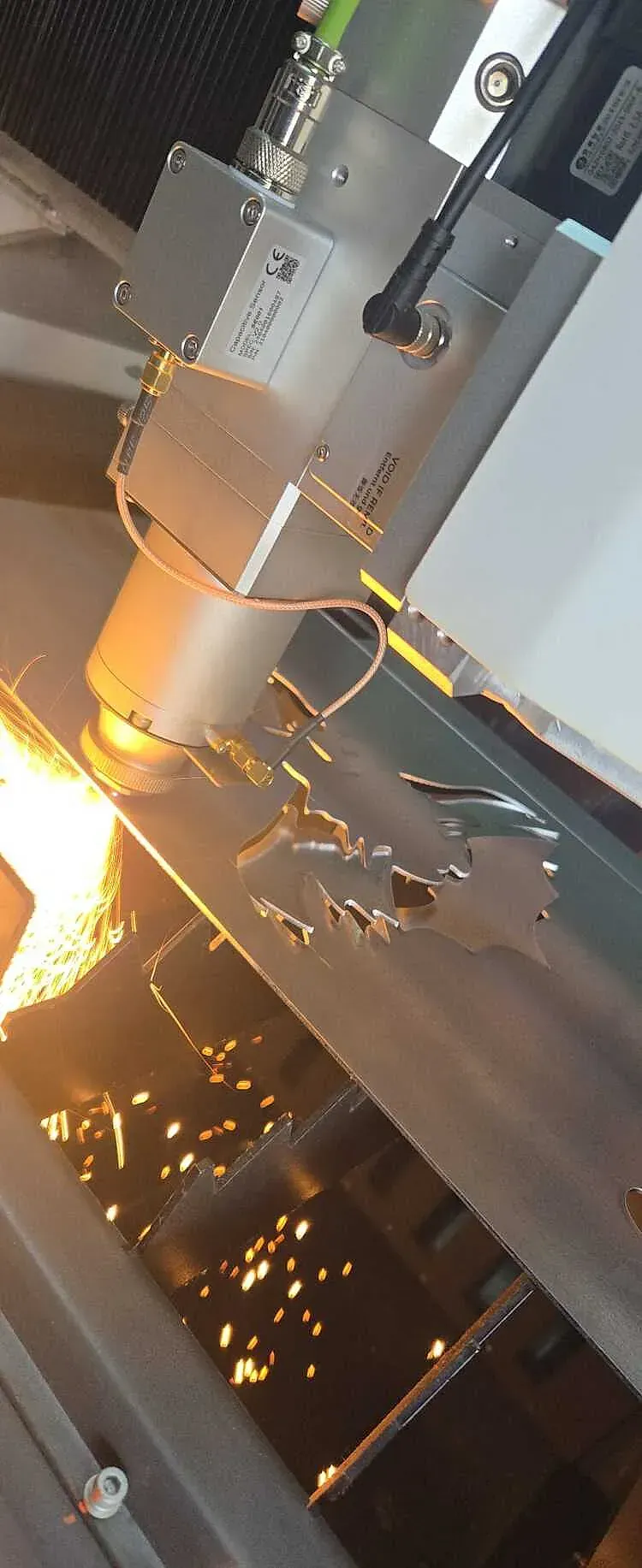 Corte por láser de chapa metálica, chispas en entorno industrial.