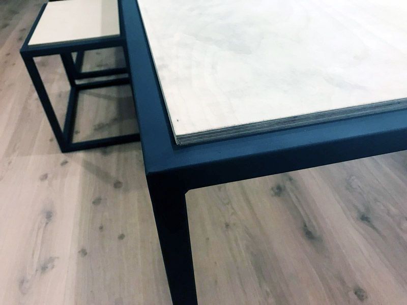 Mesa y mesa auxiliar con estructura de metal negro y superficies de madera clara, sobre suelo de madera.