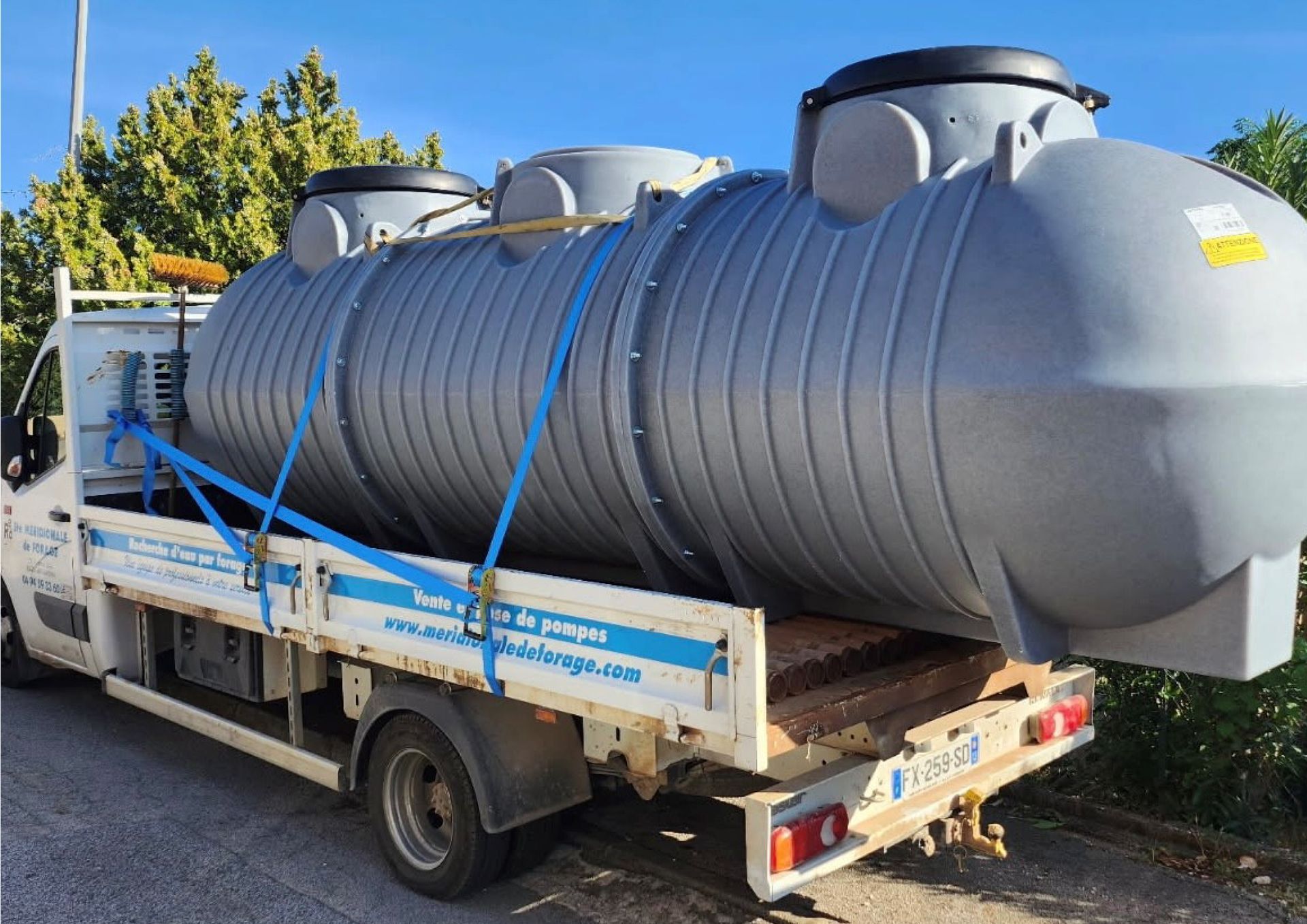 Grande cuve en plastique de réserve d'eau grise attachée à la plate-forme d'un camion pour le transport.