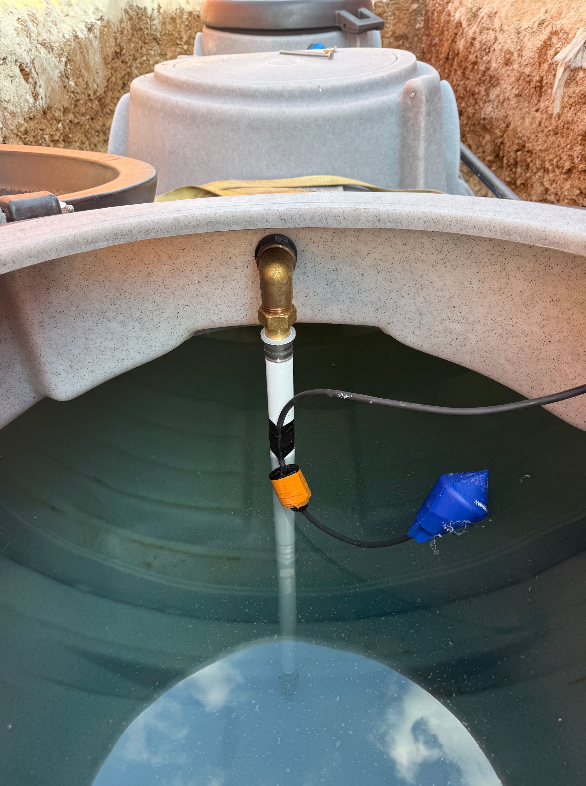 A l'intérieur du réservoir d'eau : Tuyau avec capteur et raccord en laiton, eau visible.