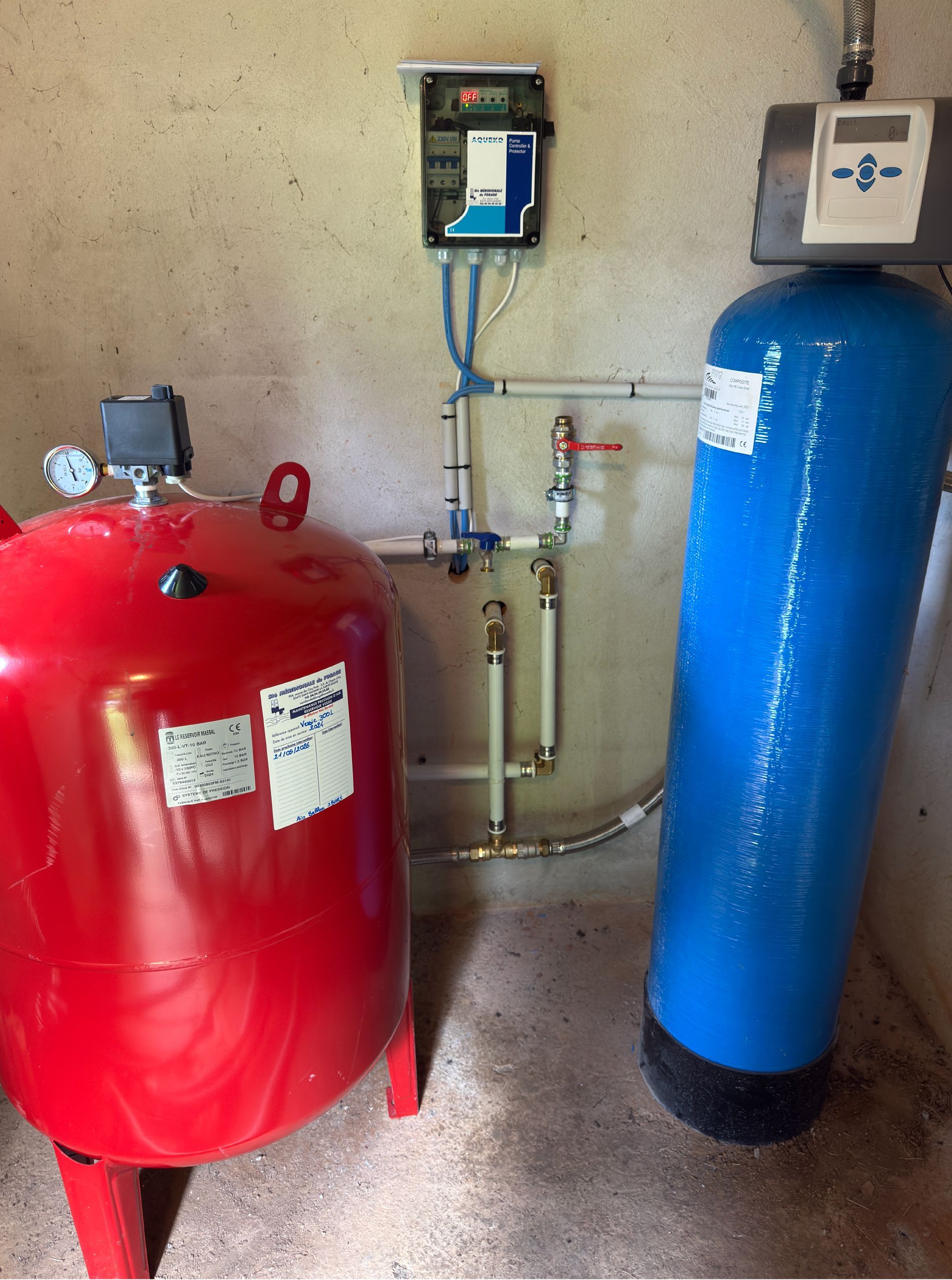 Système de réservoir d'eau rouge et bleu avec panneau de commande, tuyaux et vannes.