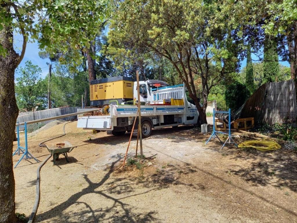 Camion avec équipement de forage dans une zone boisée; journée ensoleillée.