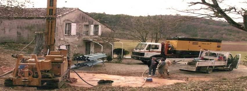 Une opération de forage est en cours près d'une maison. Des ouvriers travaillent à proximité d'une foreuse.