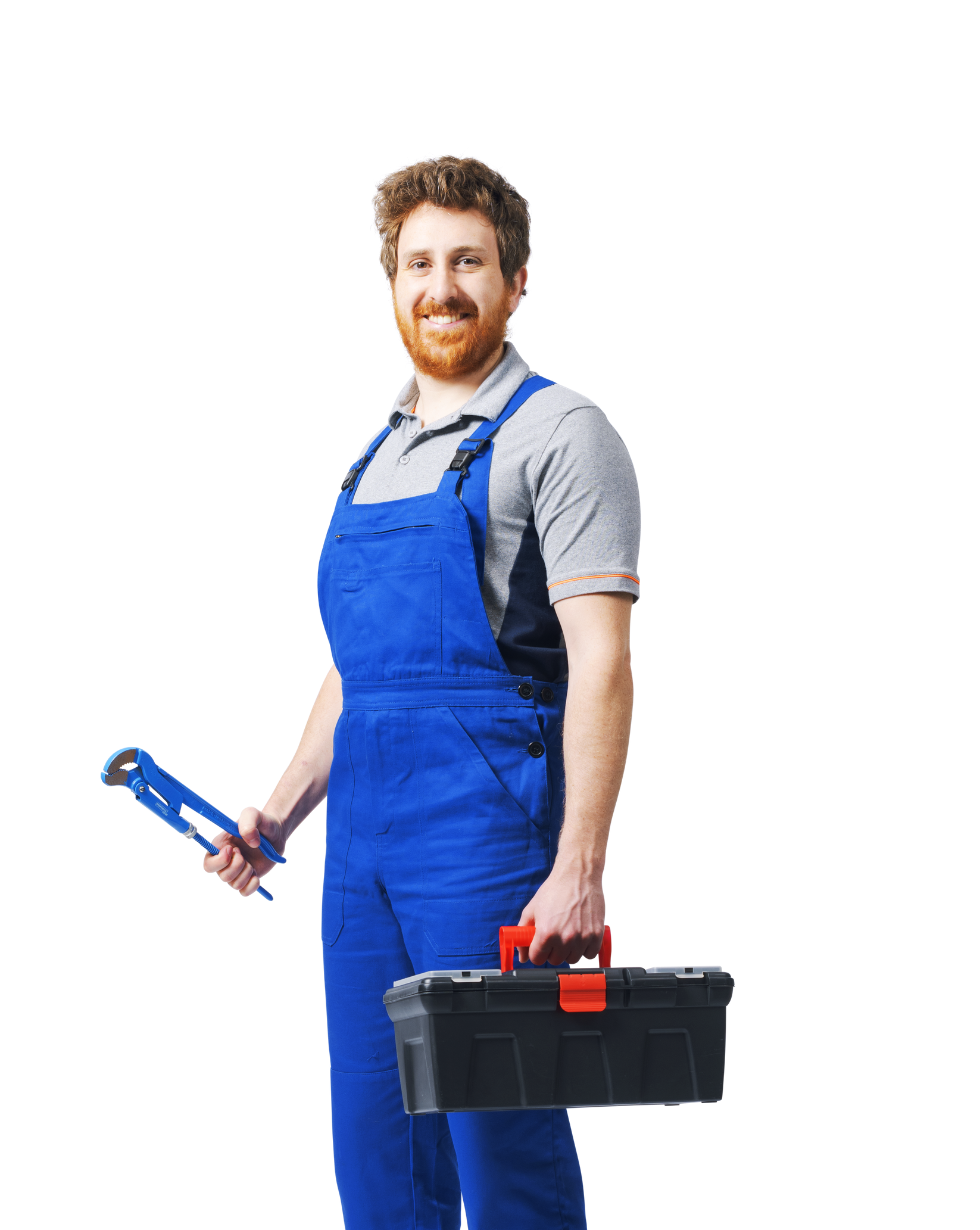 Plombier souriant aux cheveux roux, en salopette bleue, tenant une clé à molette et une boîte à outils.