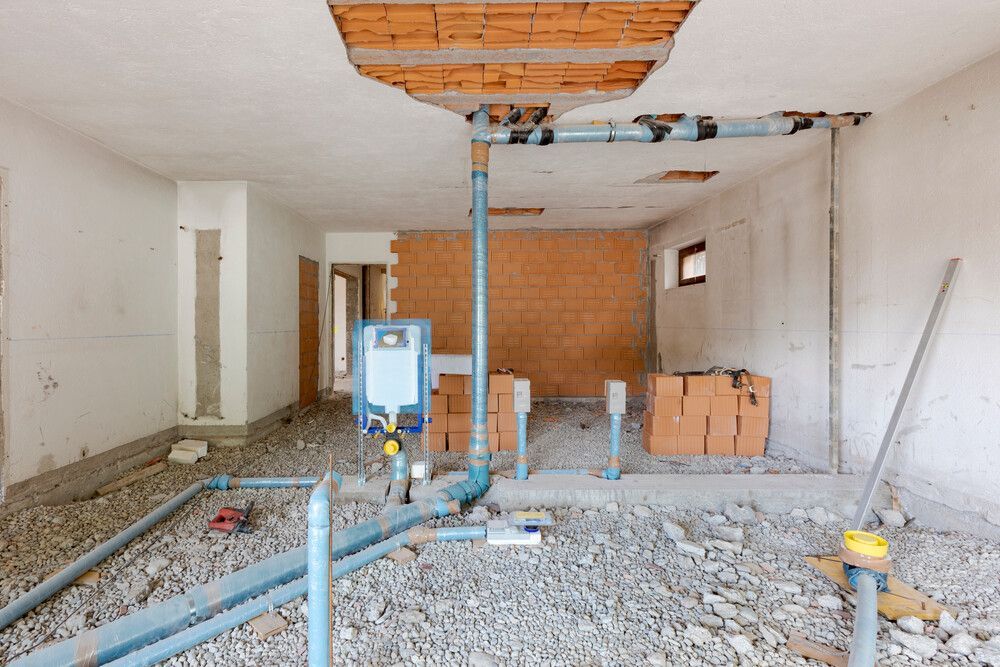 Una habitación en construcción con tuberías y ladrillos en el suelo.