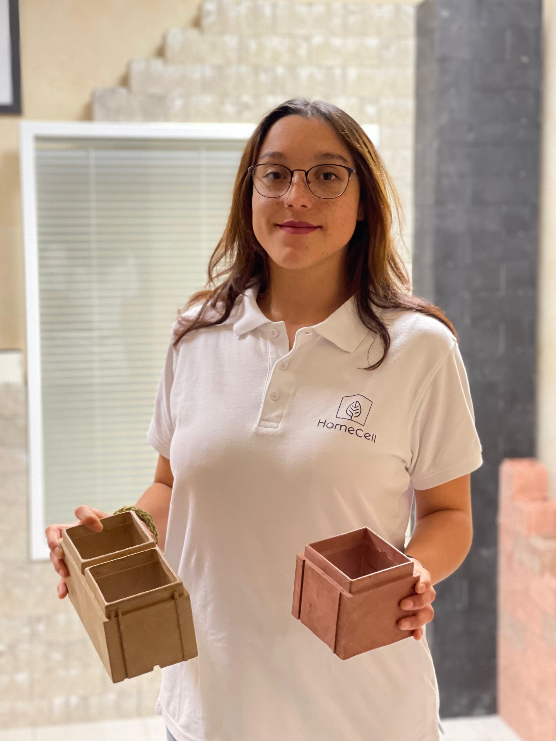 Una mujer con una camisa blanca sostiene dos cajas de madera.