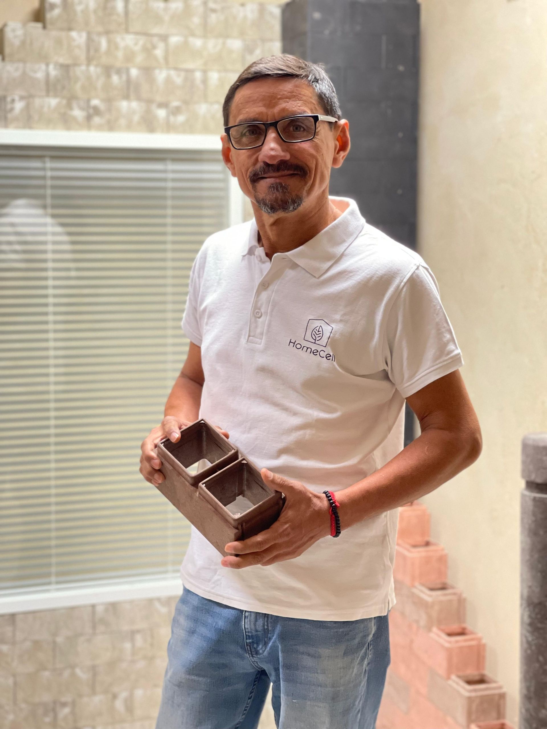 Un hombre que lleva gafas y una camisa blanca sostiene una caja de madera.