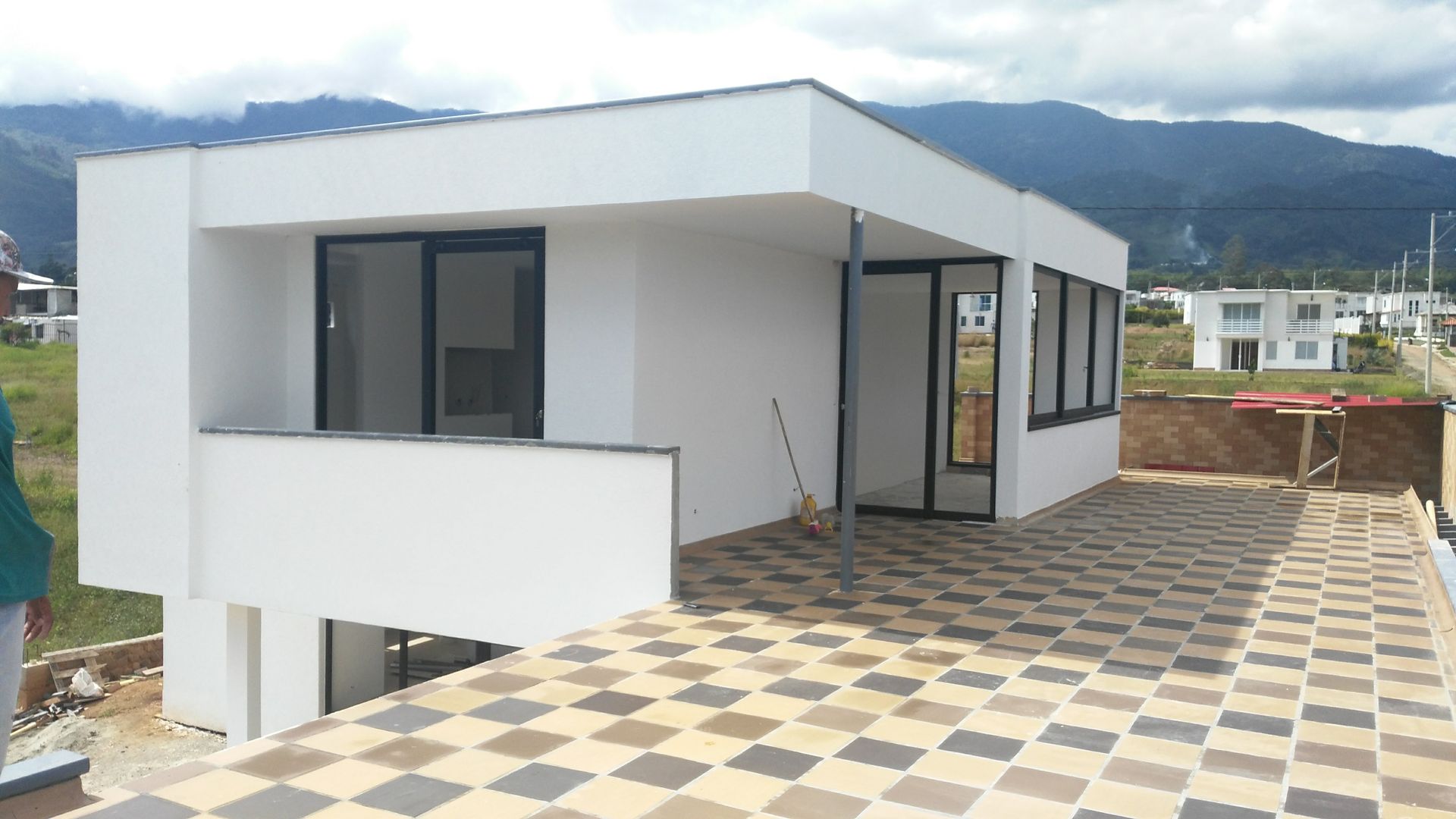 Una casa blanca con balcón y montañas al fondo.