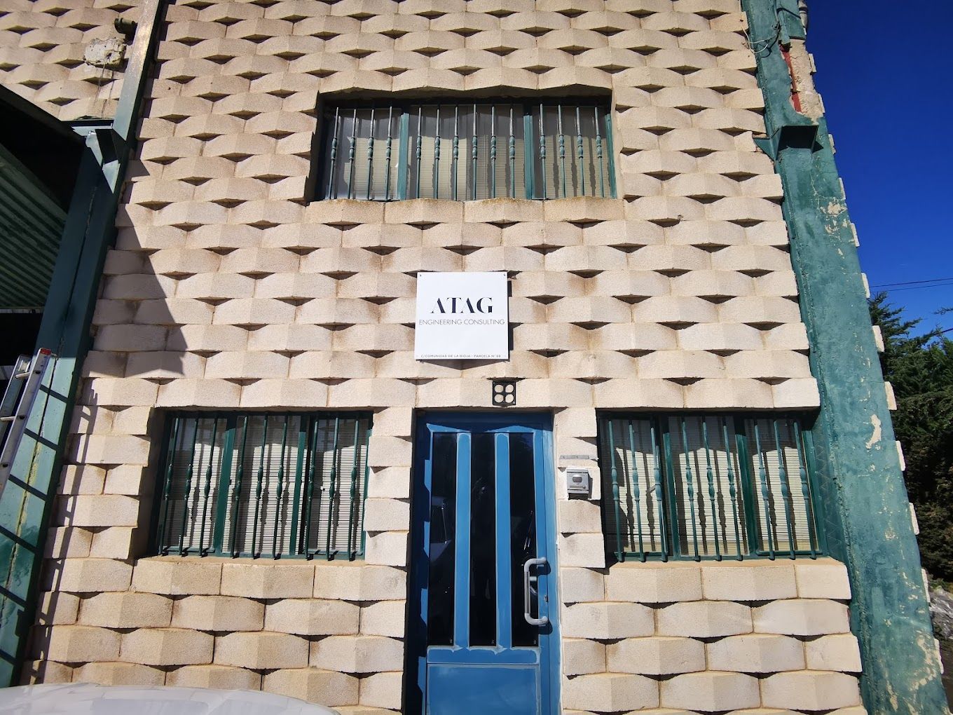 Un edificio de ladrillo con una puerta azul y un cartel que dice