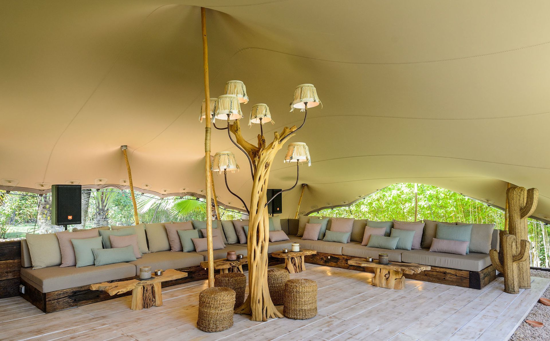 Interior de tienda de campaña de lujo con asientos, lámpara en forma de árbol y alfombra.