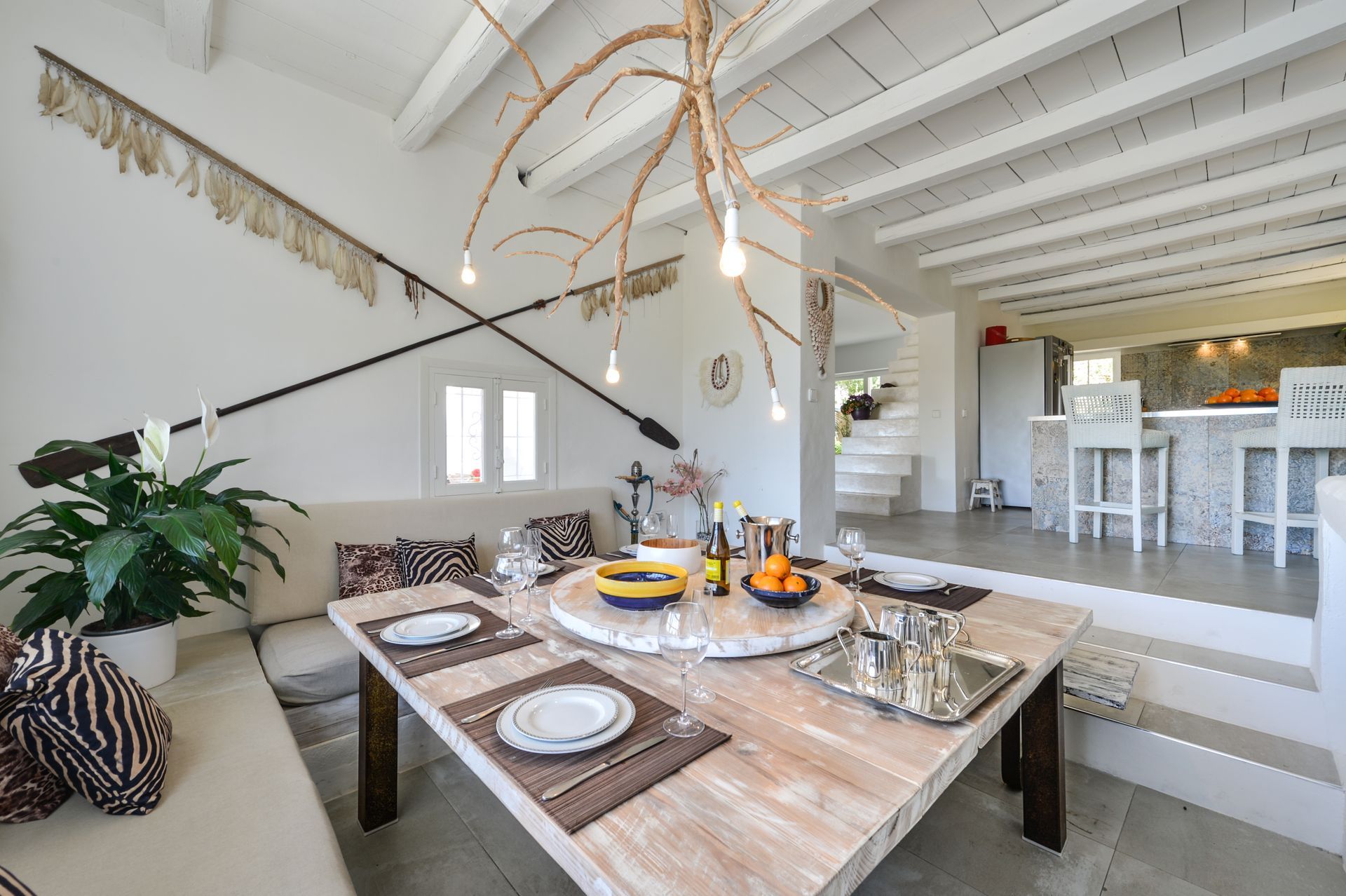 Comedor con mesa de madera, paredes blancas y vista a la cocina.