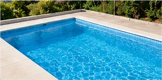 Piscina azul con agua cristalina y borde de azulejos blancos, vista desde la esquina.