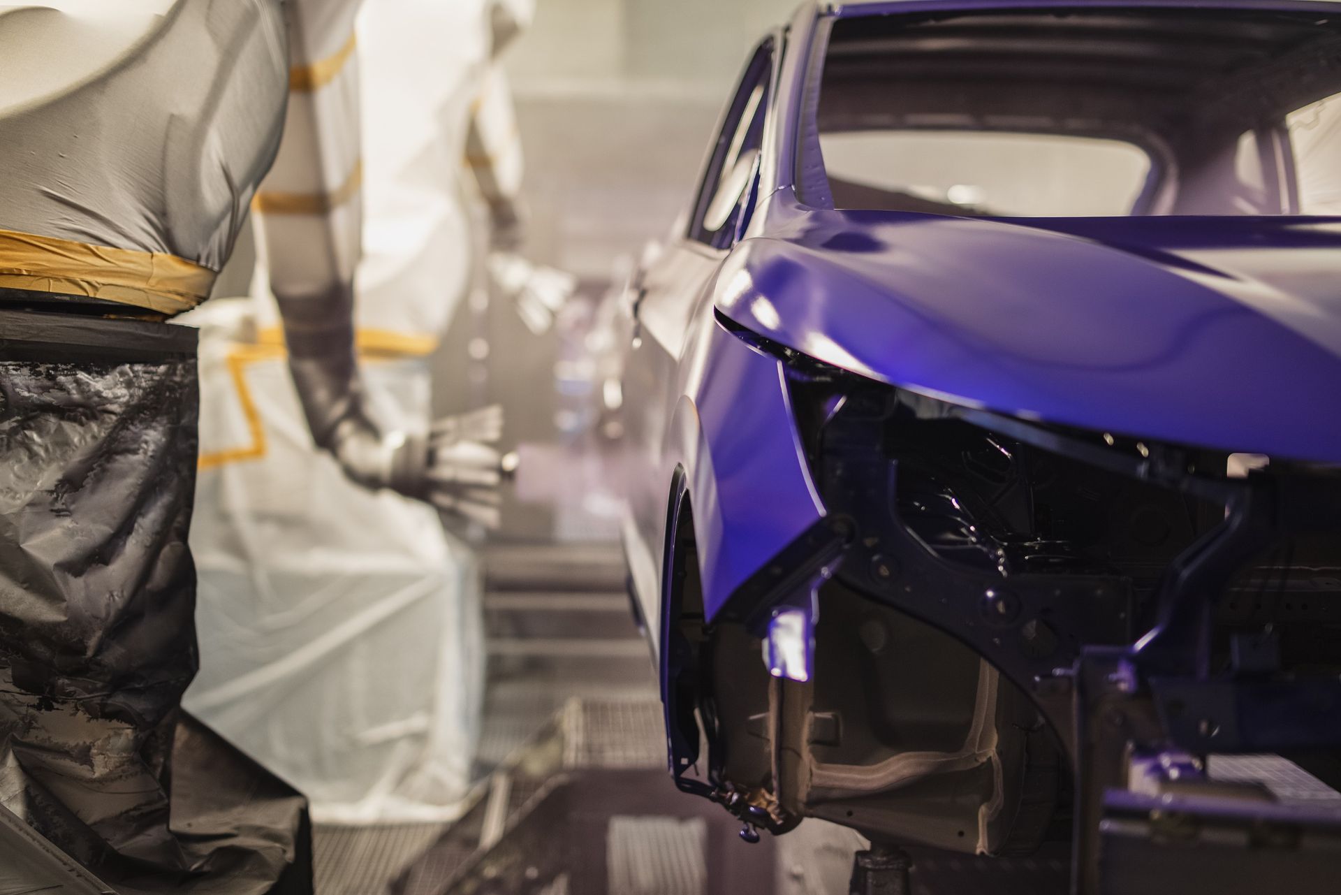 Se está pintando un coche azul en una fábrica.