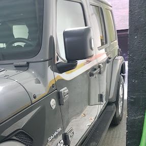 Un jeep wrangler está estacionado frente a un edificio.