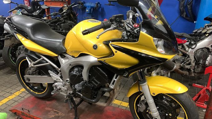 Una motocicleta amarilla está estacionada en un garaje al lado de otras motocicletas.